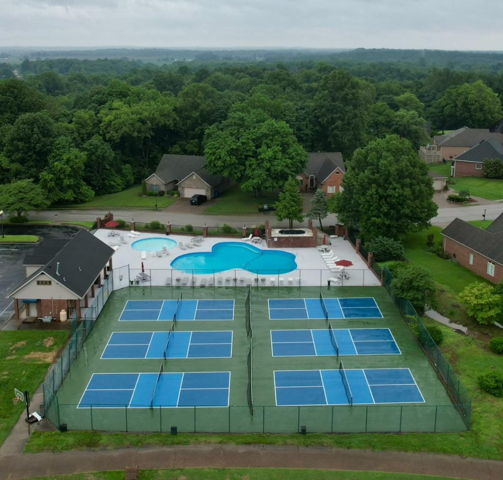 An aerial view of a tennis court with a pool in the background