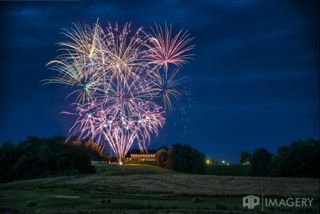 A bunch of fireworks are going off in the sky over a field.