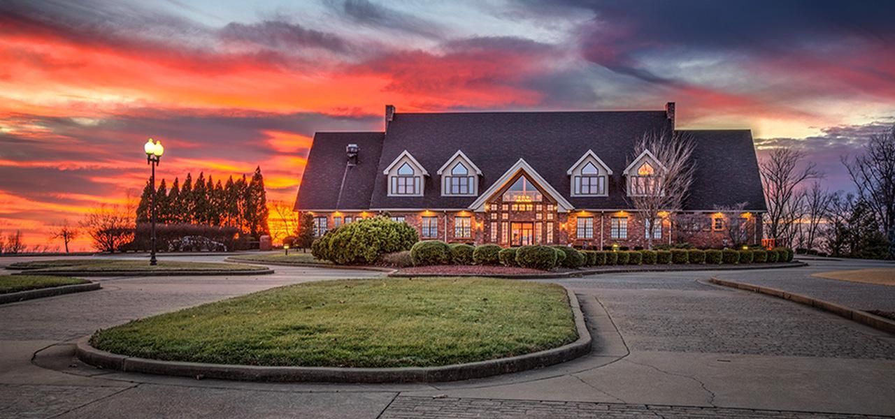 A golf course with trees in the background and a flag on the green.