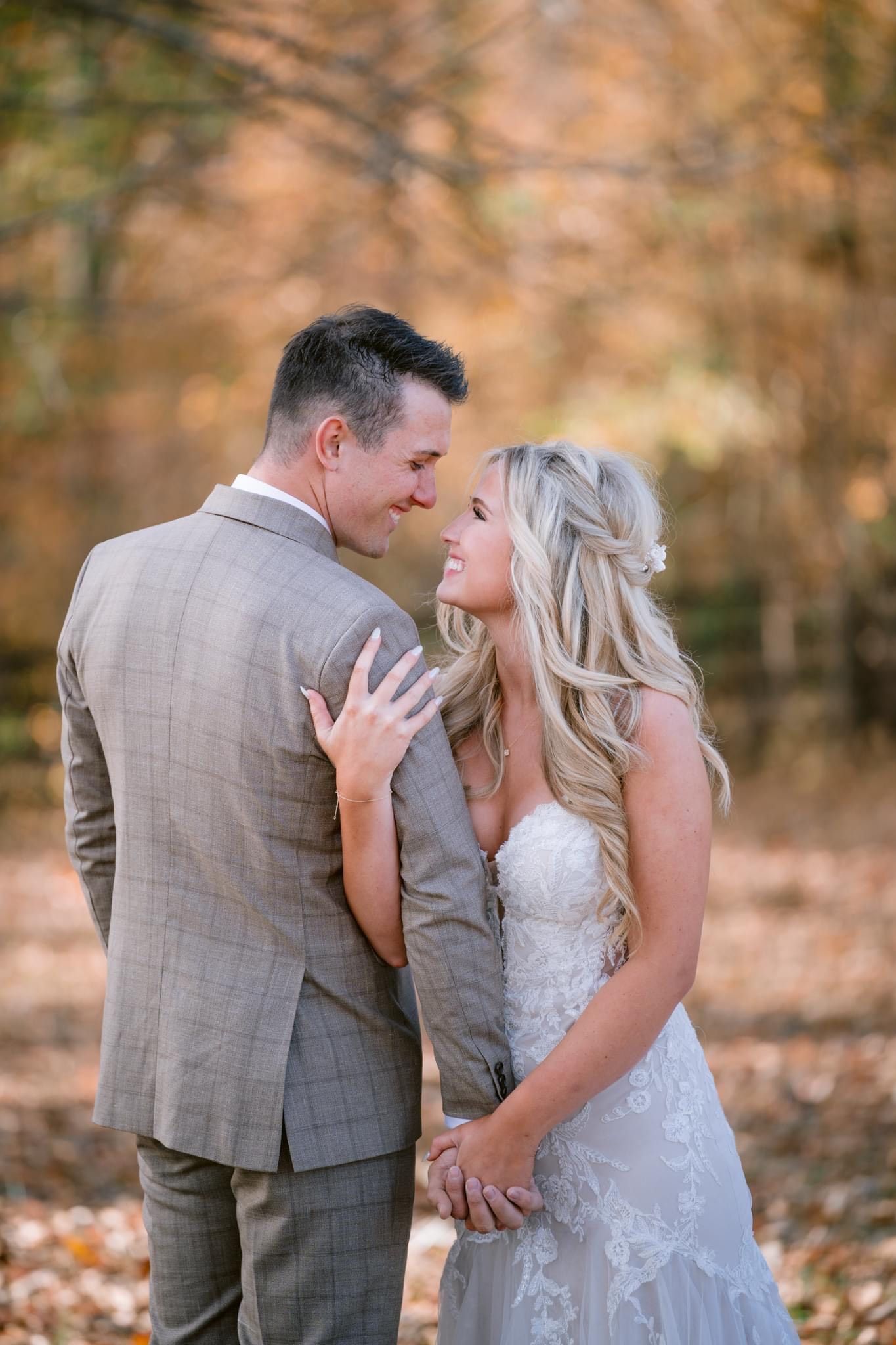 A bride and groom are posing for a picture in the woods.