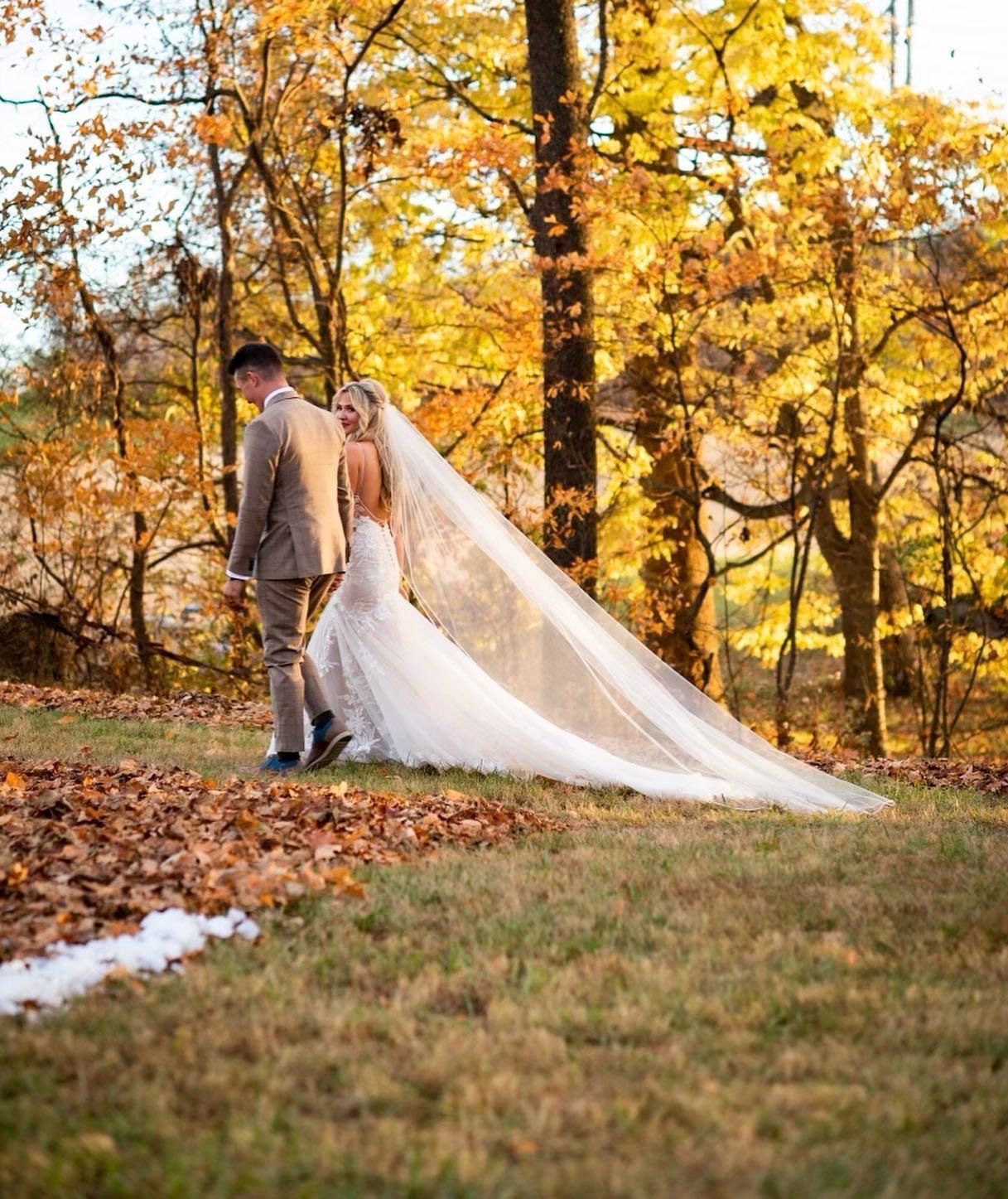 A bride and groom are walking in the woods on their wedding day.