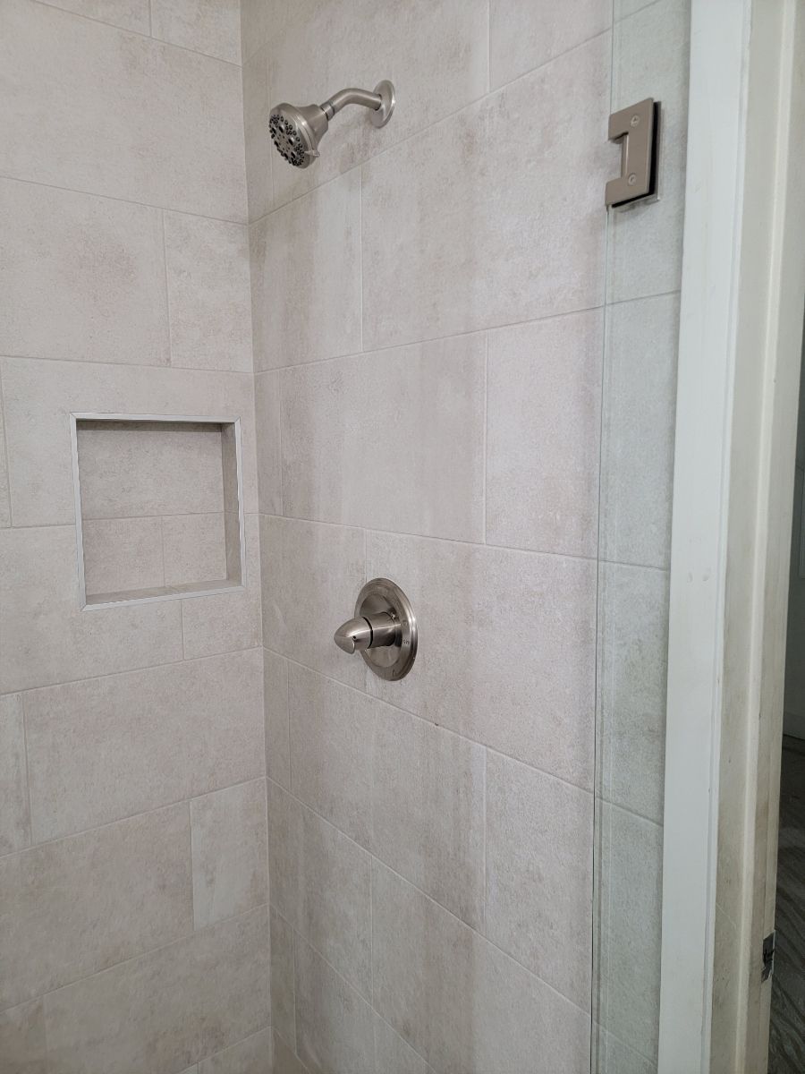 A shower with a glass door and a shower head.