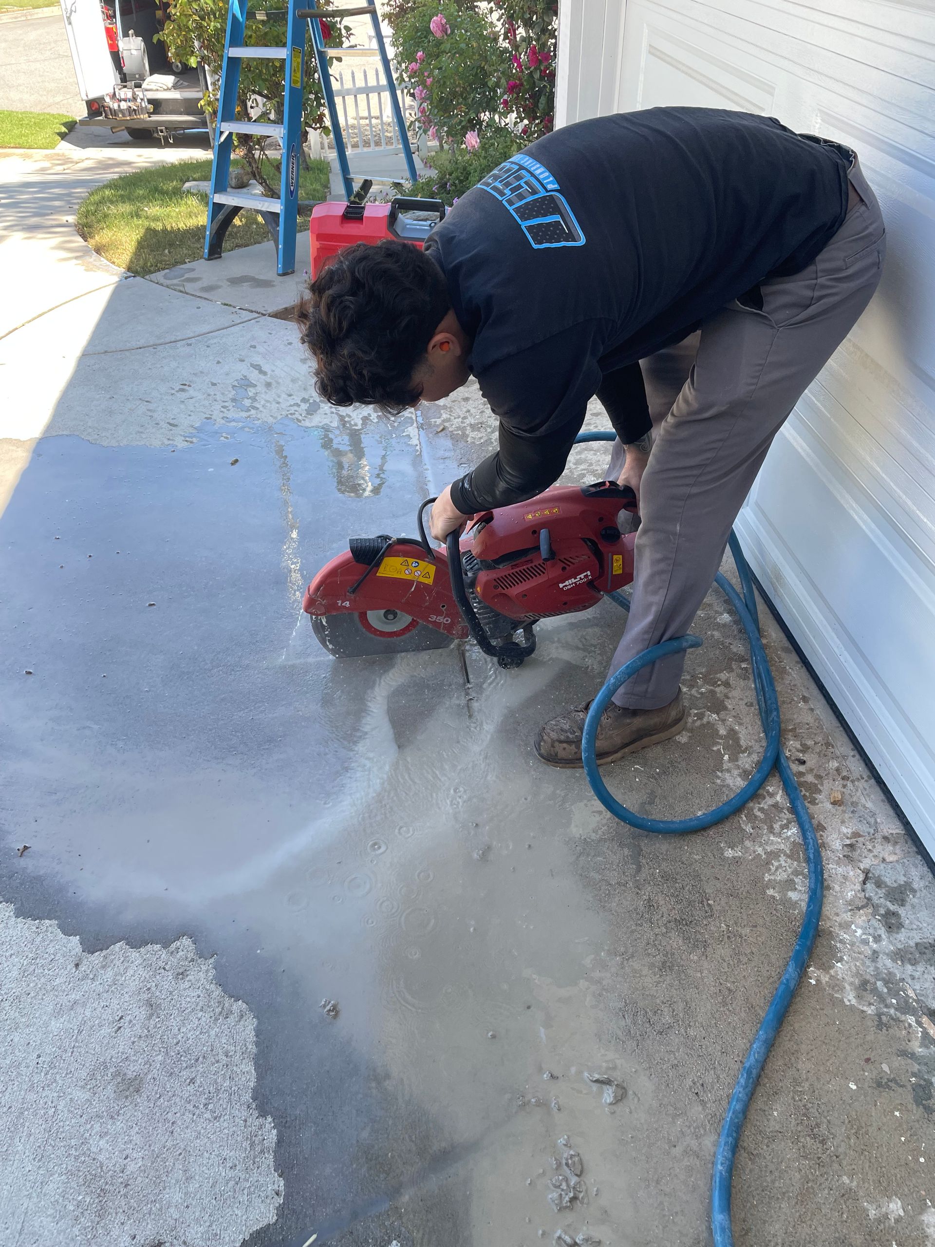 A man is using a concrete saw to cut a hole in the ground.