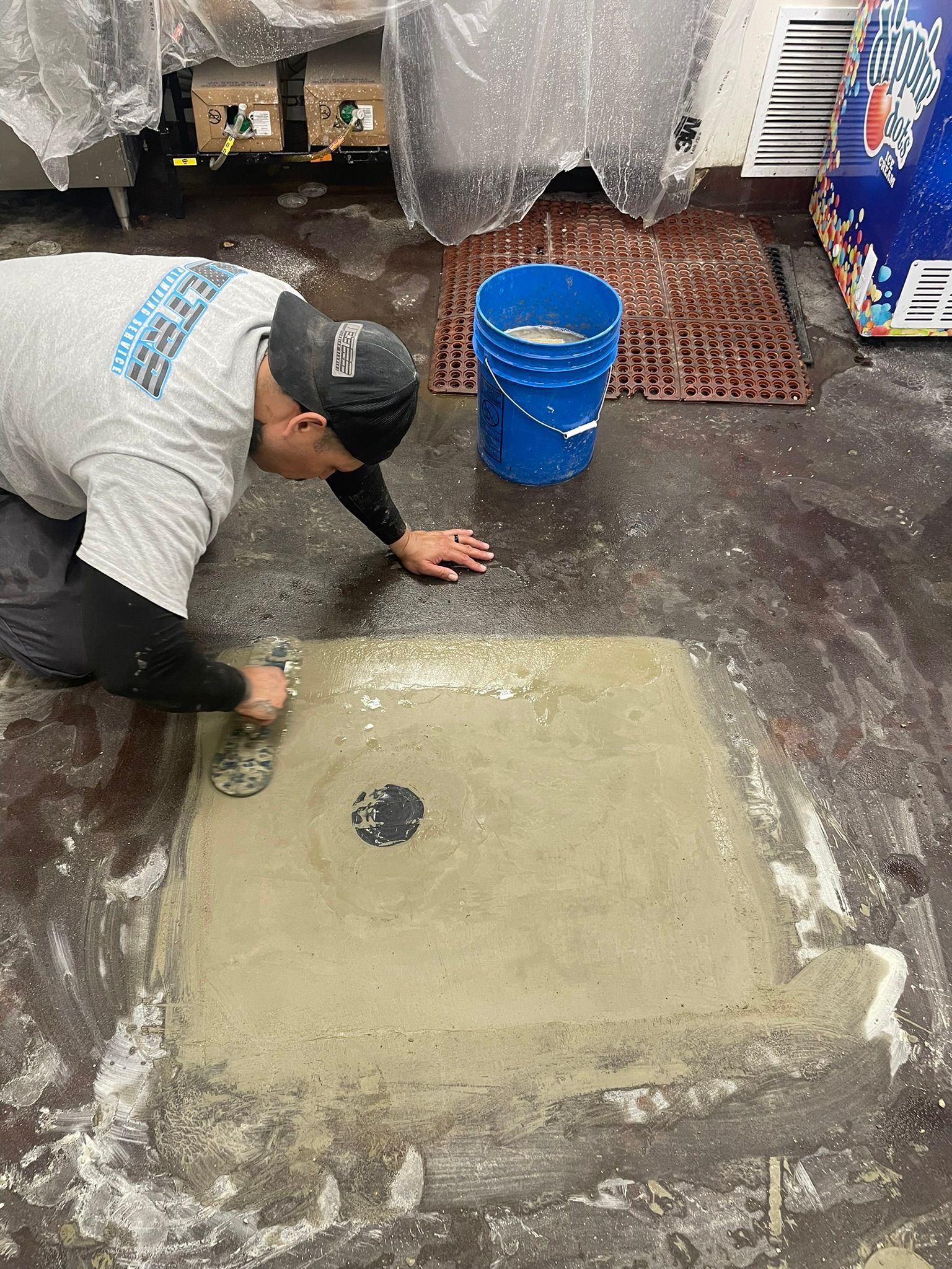 A man is working on a concrete floor in a room.
