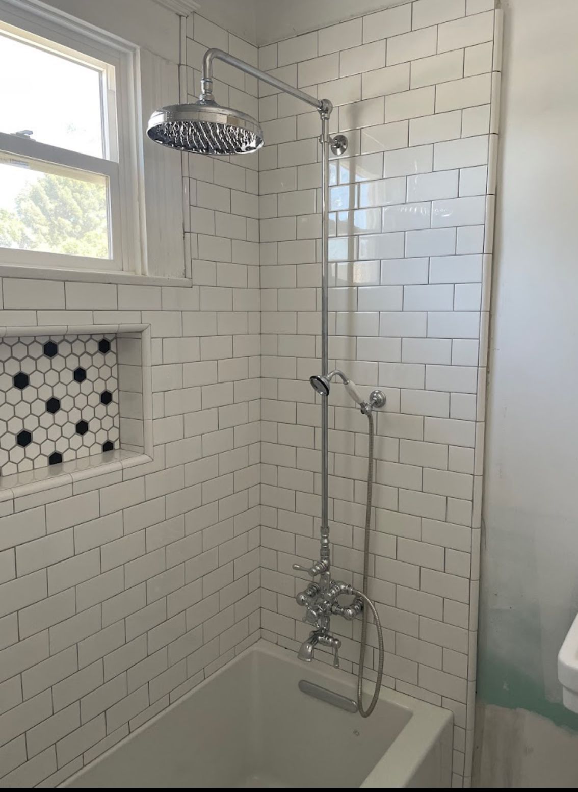 A bathroom with white tiles and a shower head