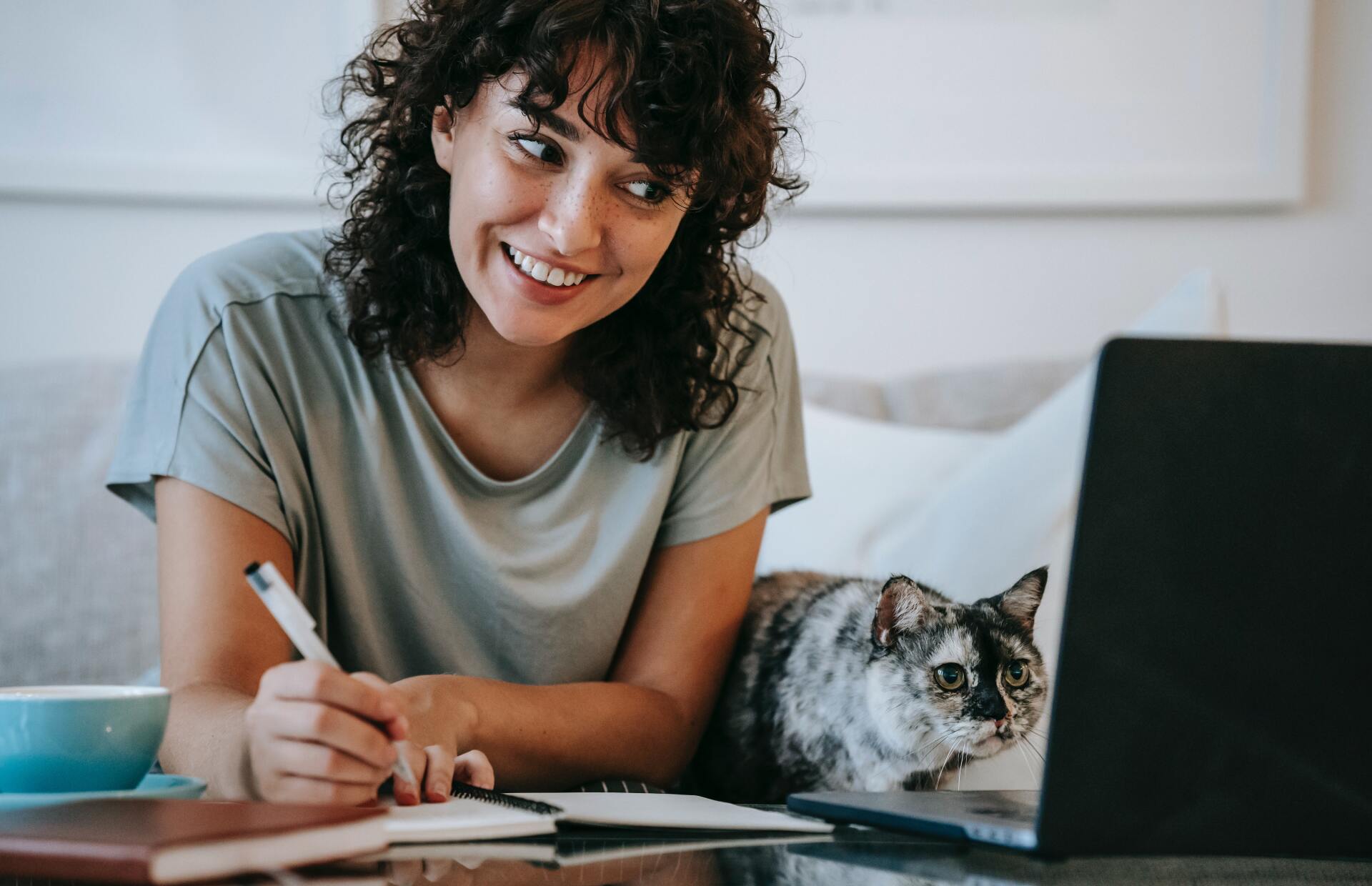 curly-haired lady and cat looking at laptop