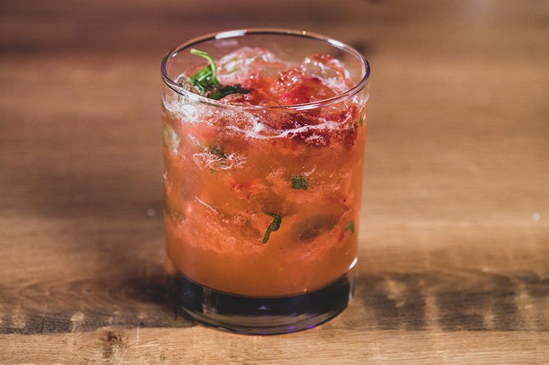 A close up of a drink in a glass on a wooden table.