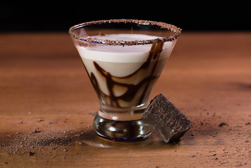 A martini glass with a chocolate swirl on a wooden table.