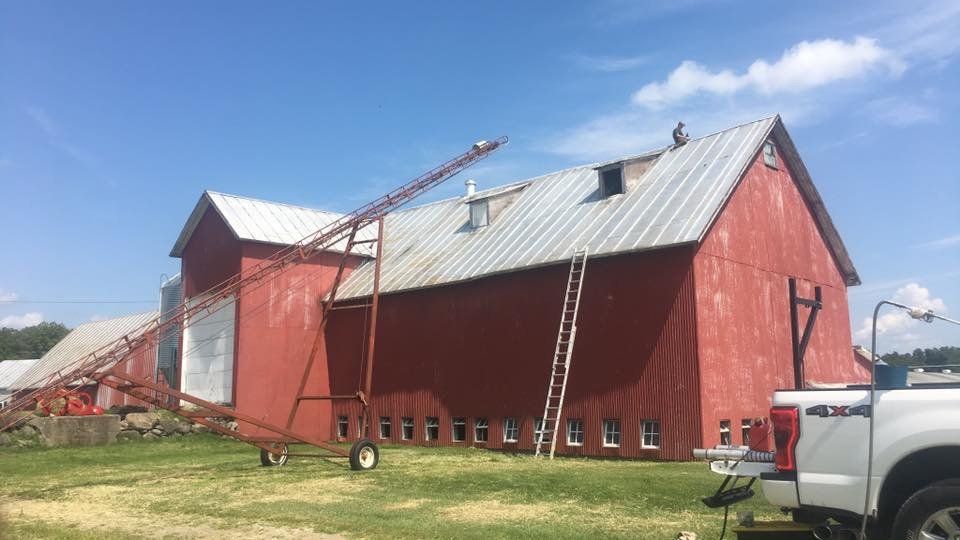a red barn with a truck parked in front of it .