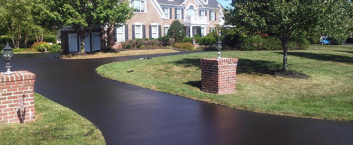 a black driveway is leading to a large house .