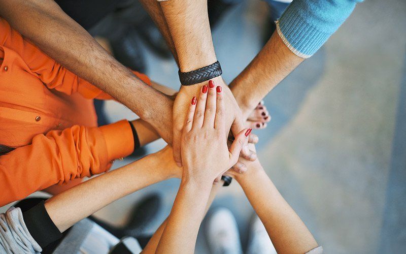 A group of people are putting their hands together in a circle.