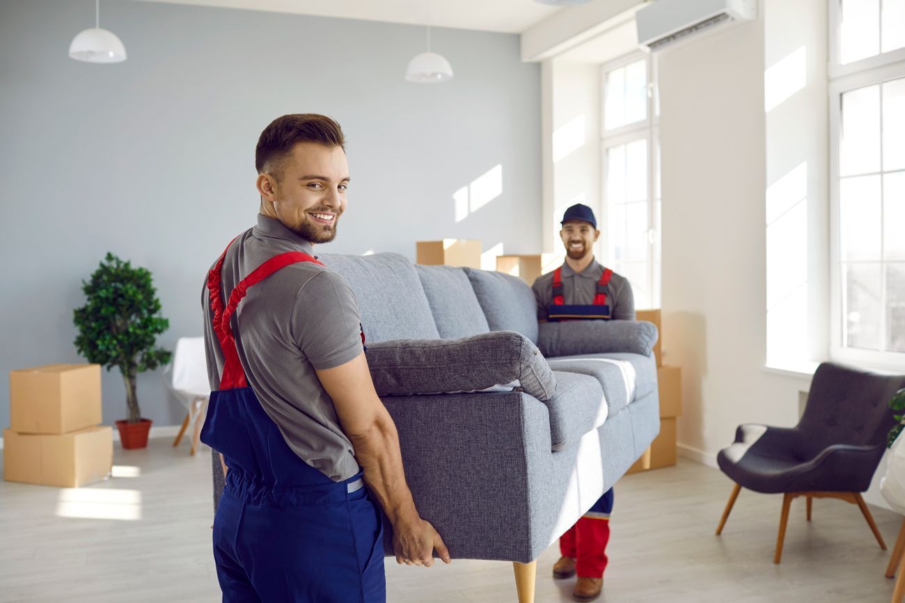 Two smiling men hold a sofa as they prepare for a move, showcasing expert moving company services.
