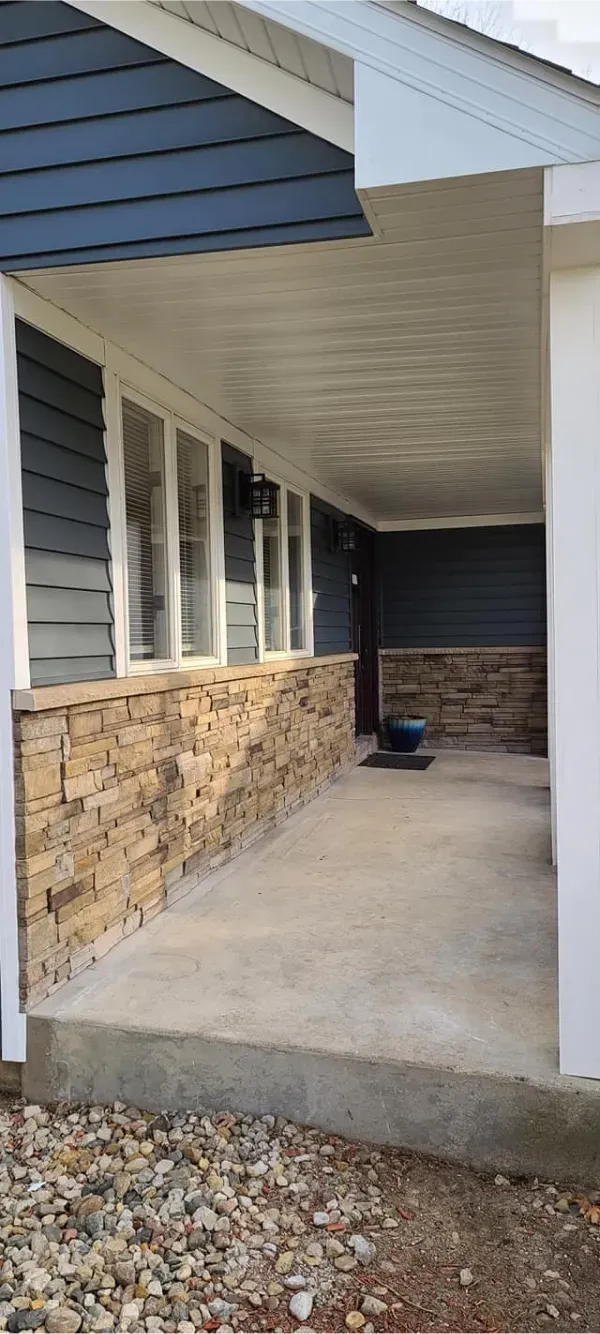 A porch with a concrete walkway leading to the front door of a house.