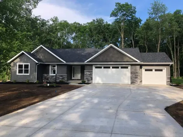A house with a driveway and trees in the background