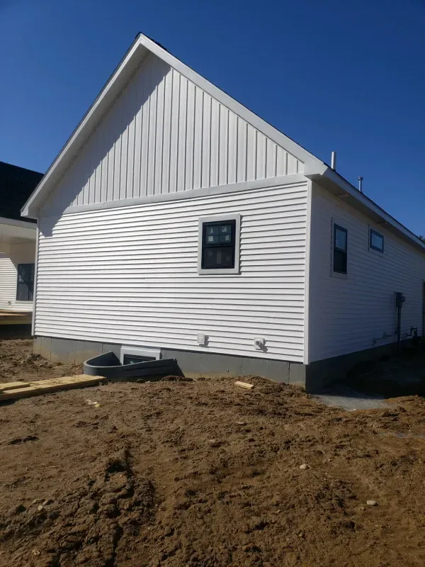 A white house is sitting in the middle of a dirt field.