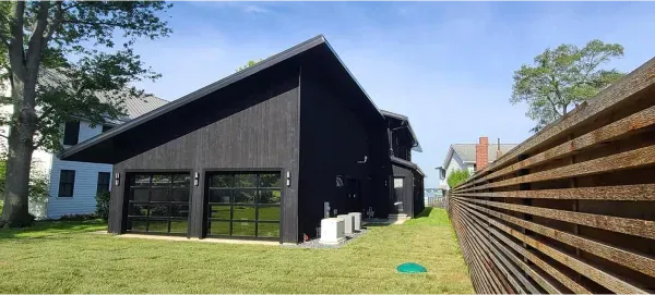 A black house with a wooden fence in front of it.