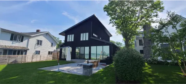 A large black house with a lot of windows is sitting on top of a lush green lawn.