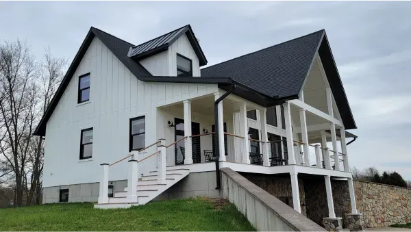 A large white house with a black roof and porch