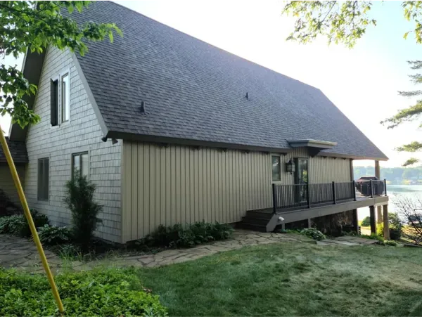 A large house with a large deck overlooking a body of water