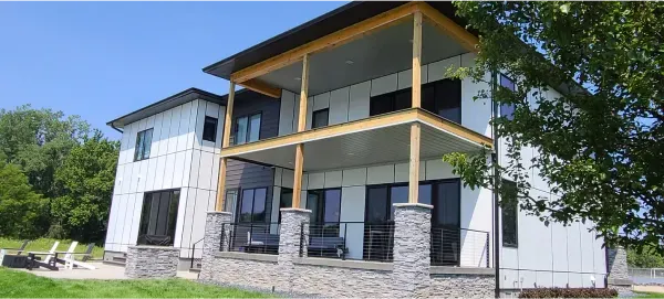 A large white house with a porch and a tree in front of it.