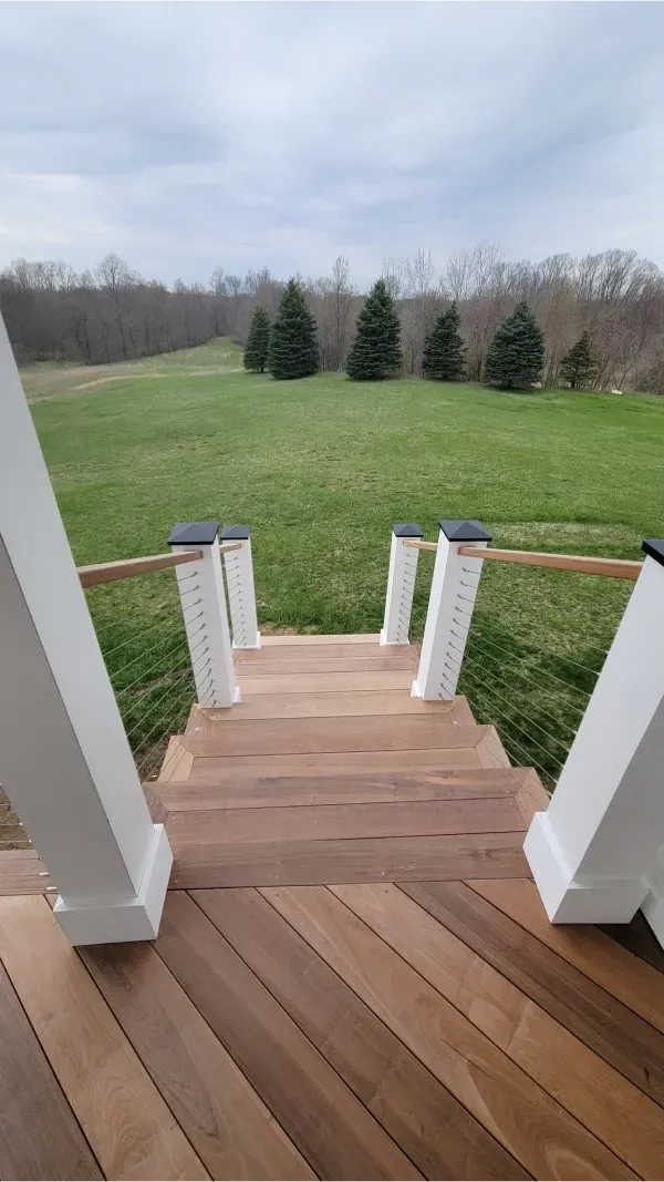 A wooden deck with stairs leading up to a grassy field.