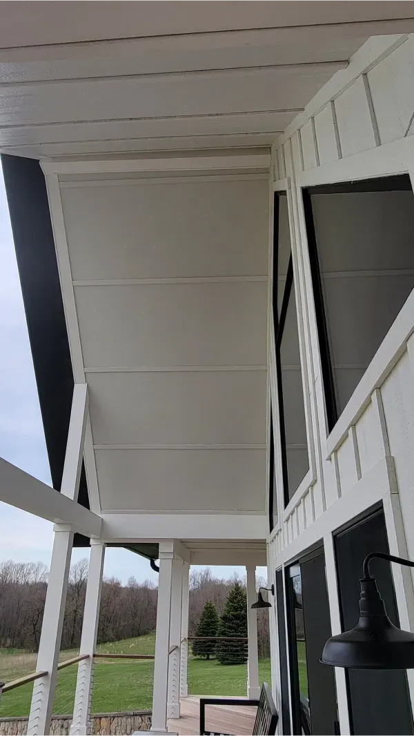 A white house with a porch and a view of a field.