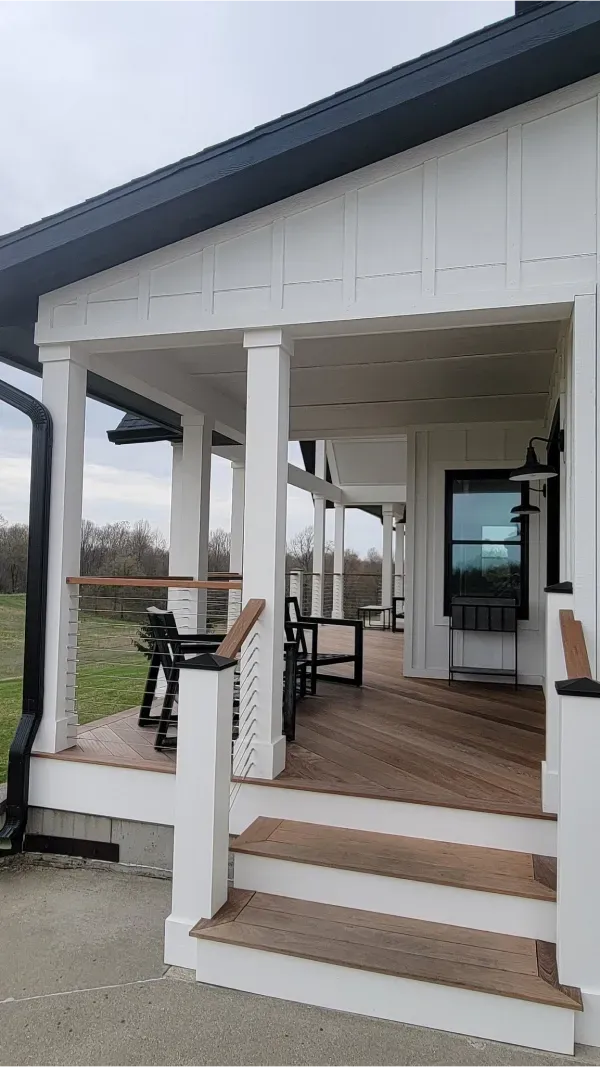 A white house with a porch and stairs leading up to it.