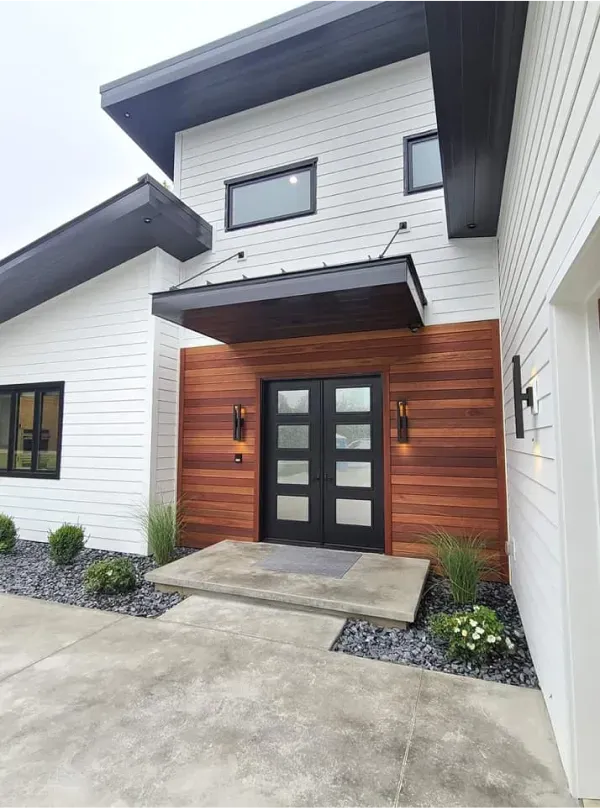 A white house with wood paneling and a black door
