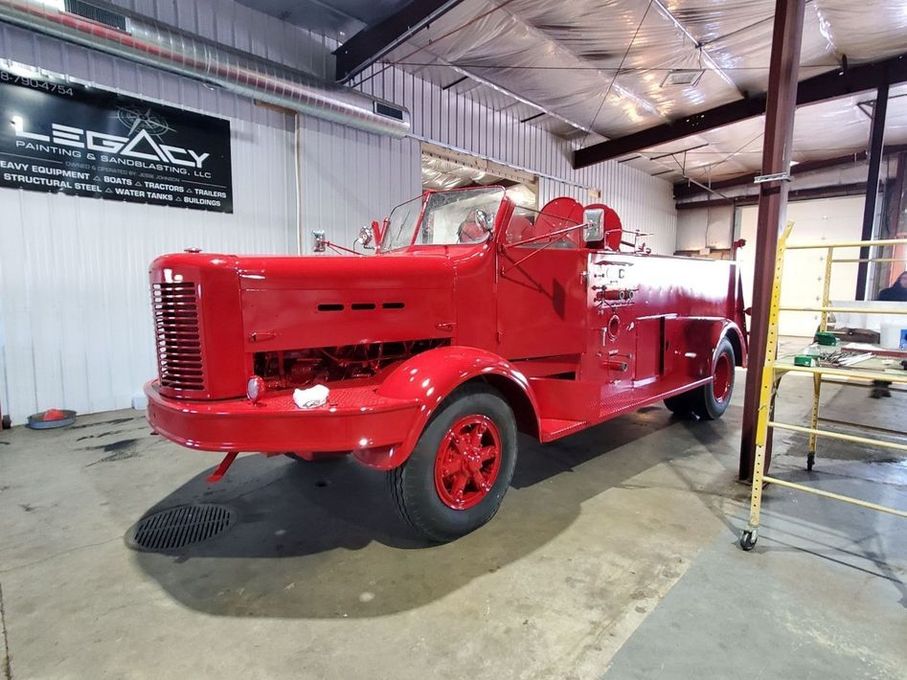 Red vintage fire truck in a garage, under renovation.