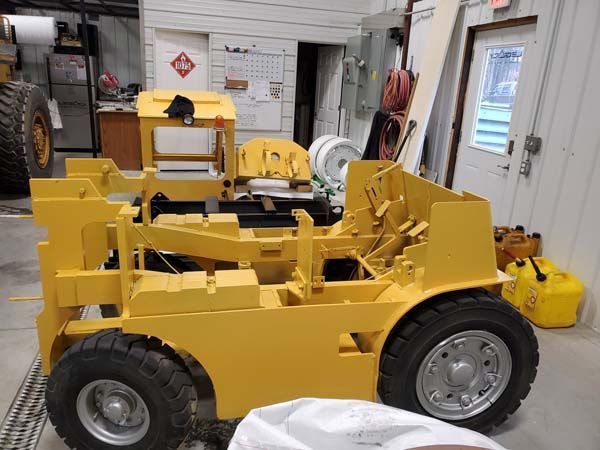 Yellow forklift with black tires inside a workshop.