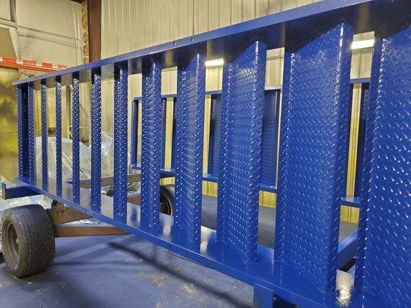 Blue diamond-plated metal cart with vertical bars, resting on tires.