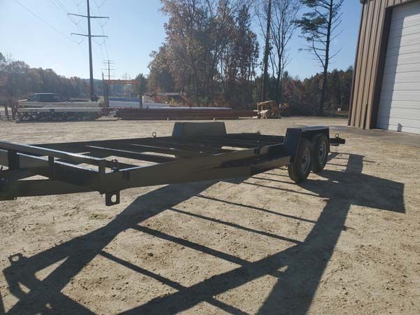 Empty, dark-painted trailer on a sunny day, with a building in the background.