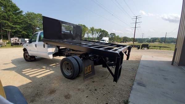 White flatbed truck with black bed on gravel.