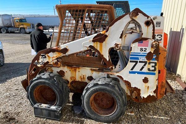 Rusty Bobcat S2, 773 model, parked outside. A person stands nearby.