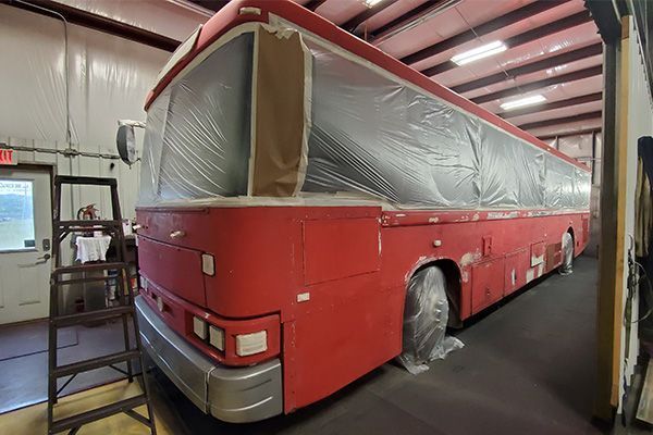 Red bus in a workshop, masked for painting.