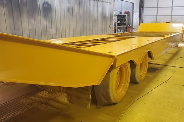 Yellow industrial trailer in a paint booth.