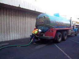 Septic truck with hose going into commercial building