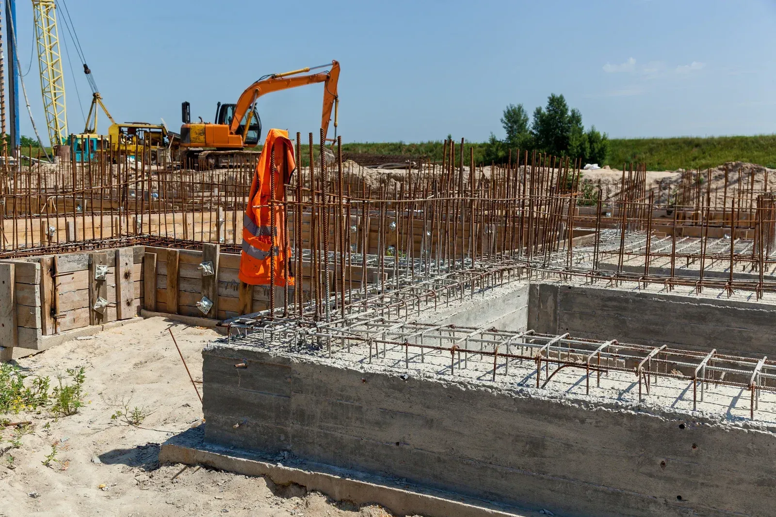 A construction site with a yellow excavator in the background.