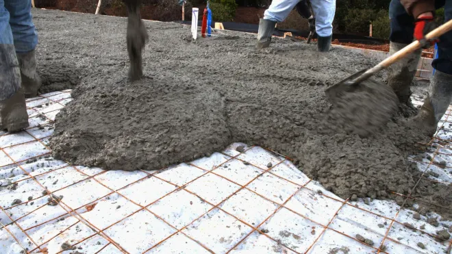 A group of people are pouring concrete on a tiled floor.