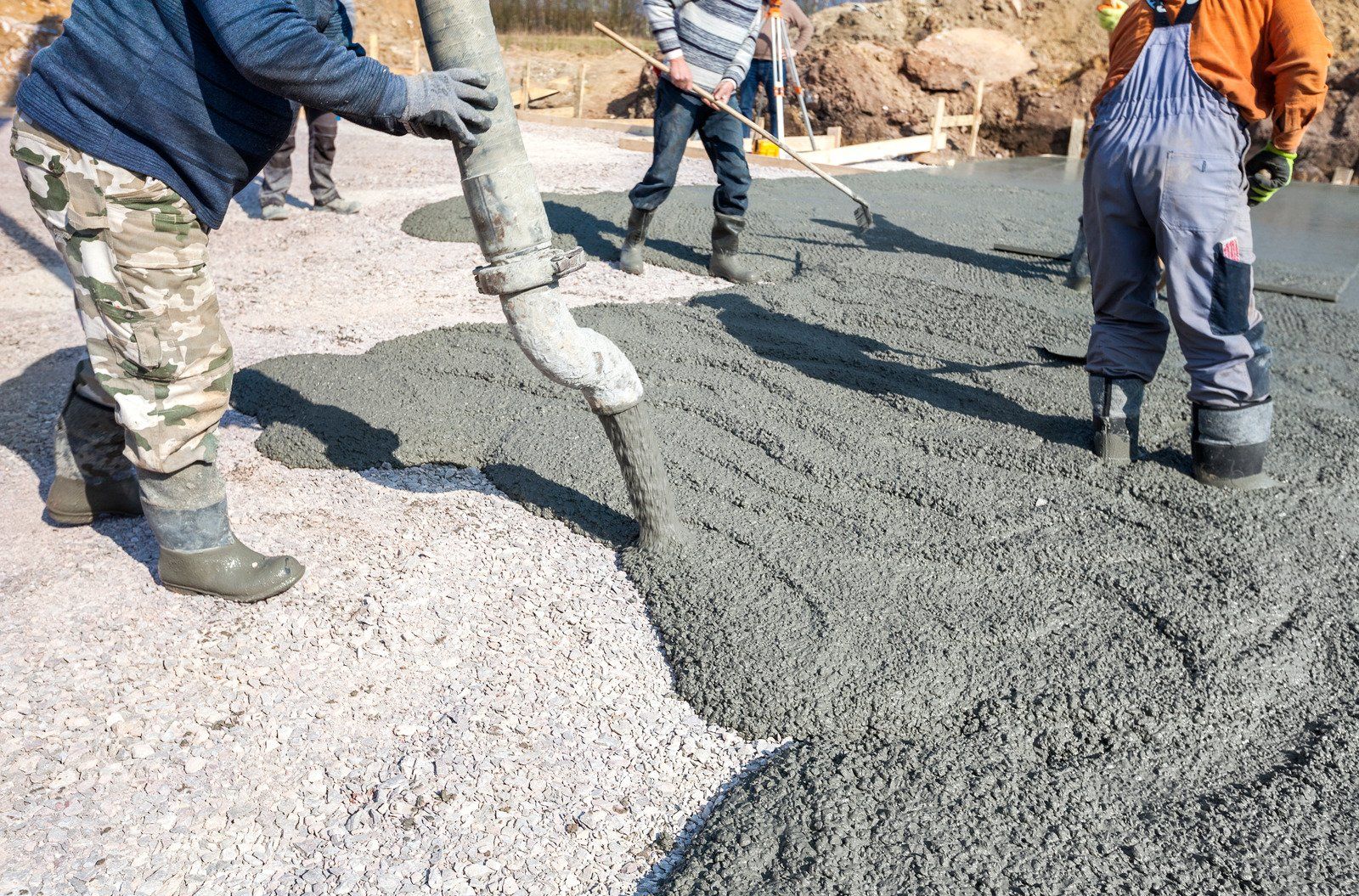 A group of construction workers are pouring concrete on a road.