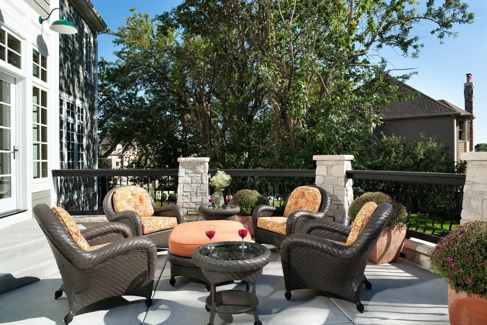 A patio with wicker furniture and a table with wine glasses on it
