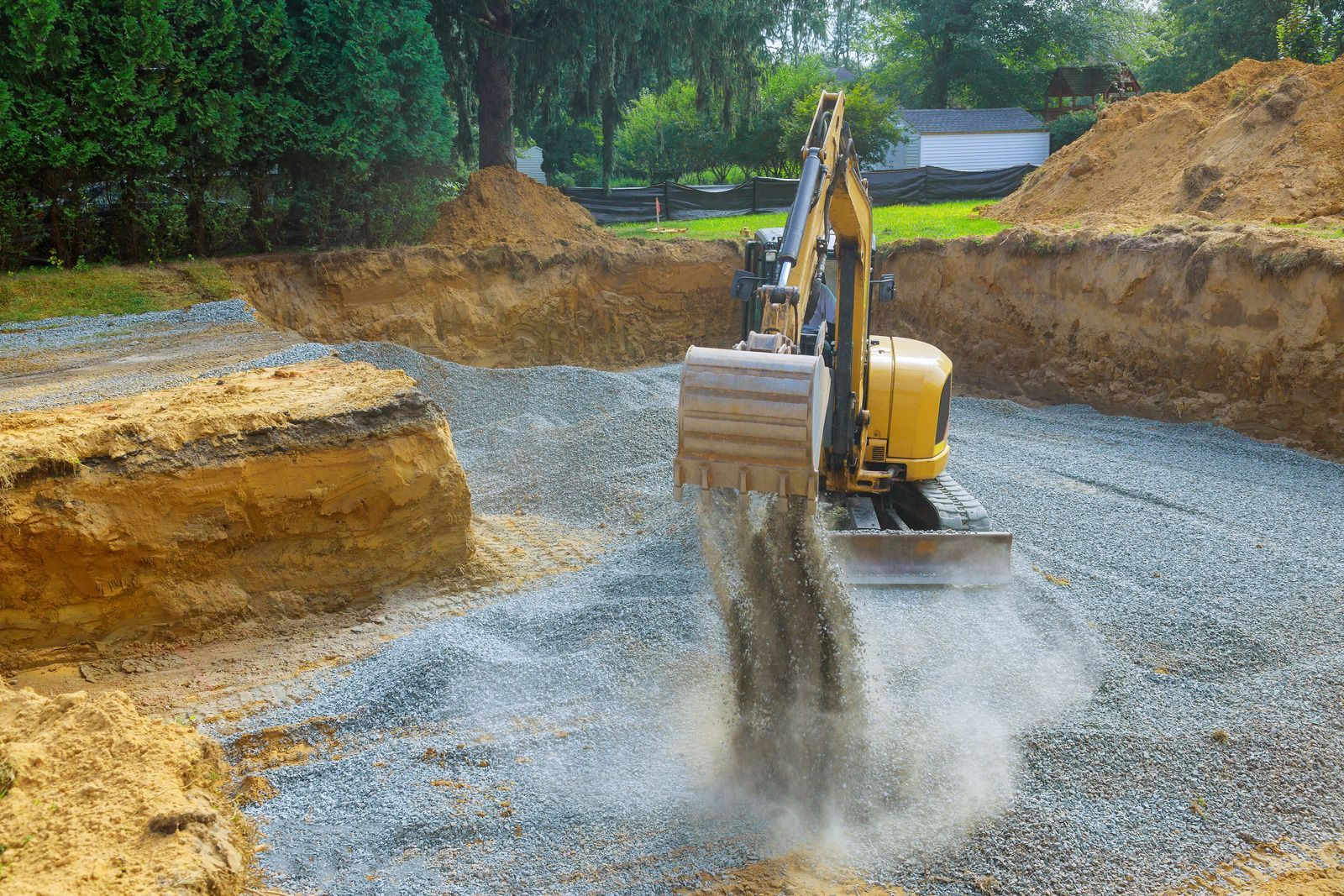 A yellow excavator is digging a hole in the ground.