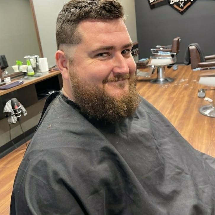 Man With Beard Smiling In Barber Cape — Bolton Brothers Barbers in Erina, NSW