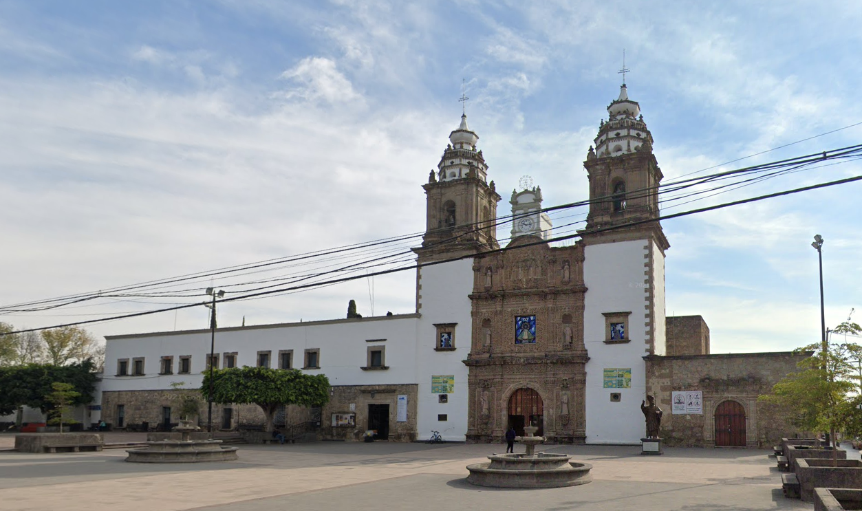 Un gran edificio blanco con una torre de reloj en frente.