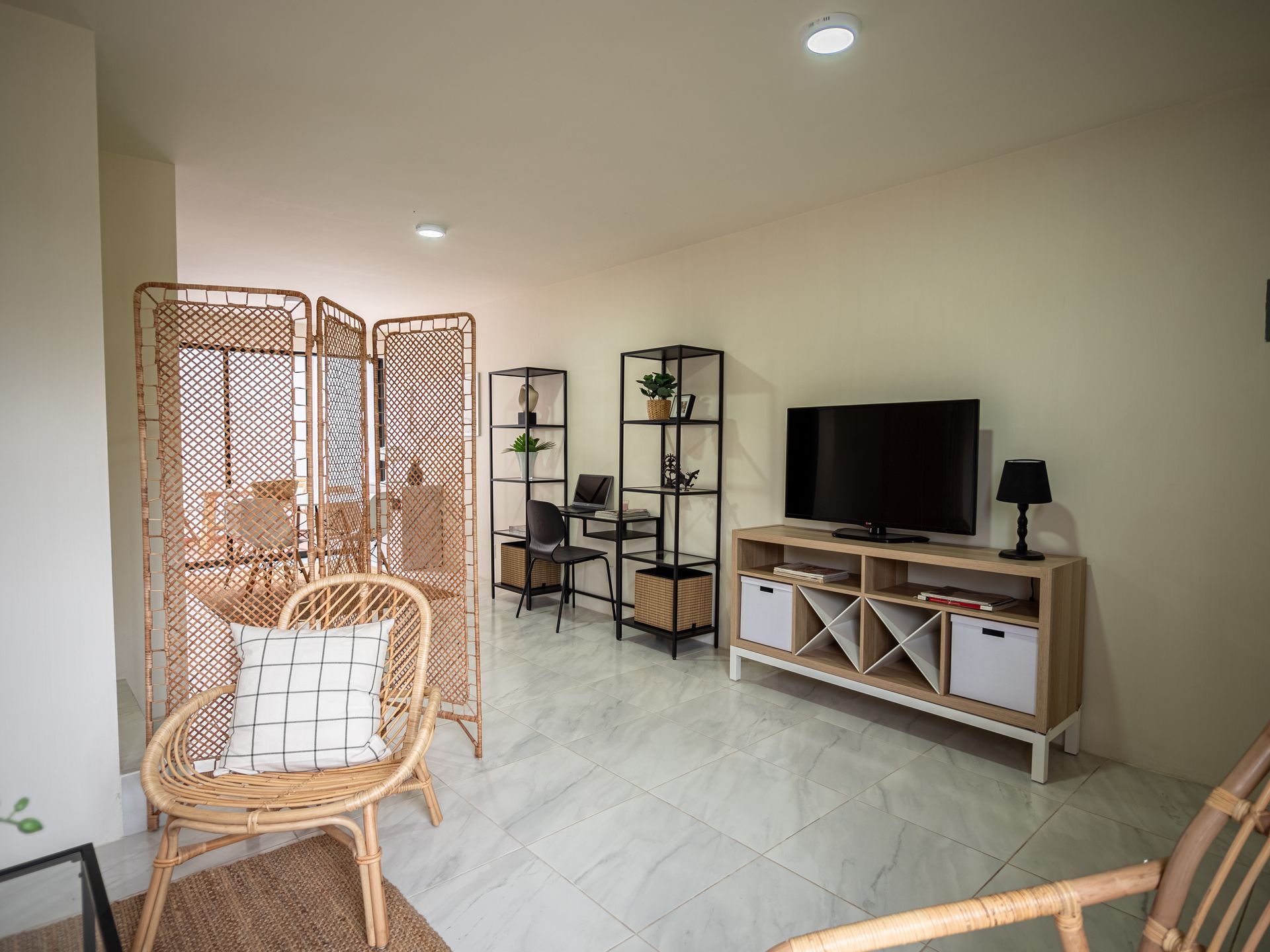 Una sala de estar con una silla de mimbre y un televisor.