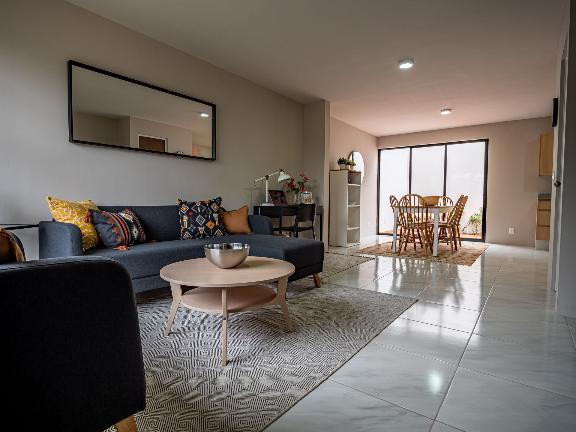 Una sala de estar con un sofá, sillas, una mesa de café y un espejo.