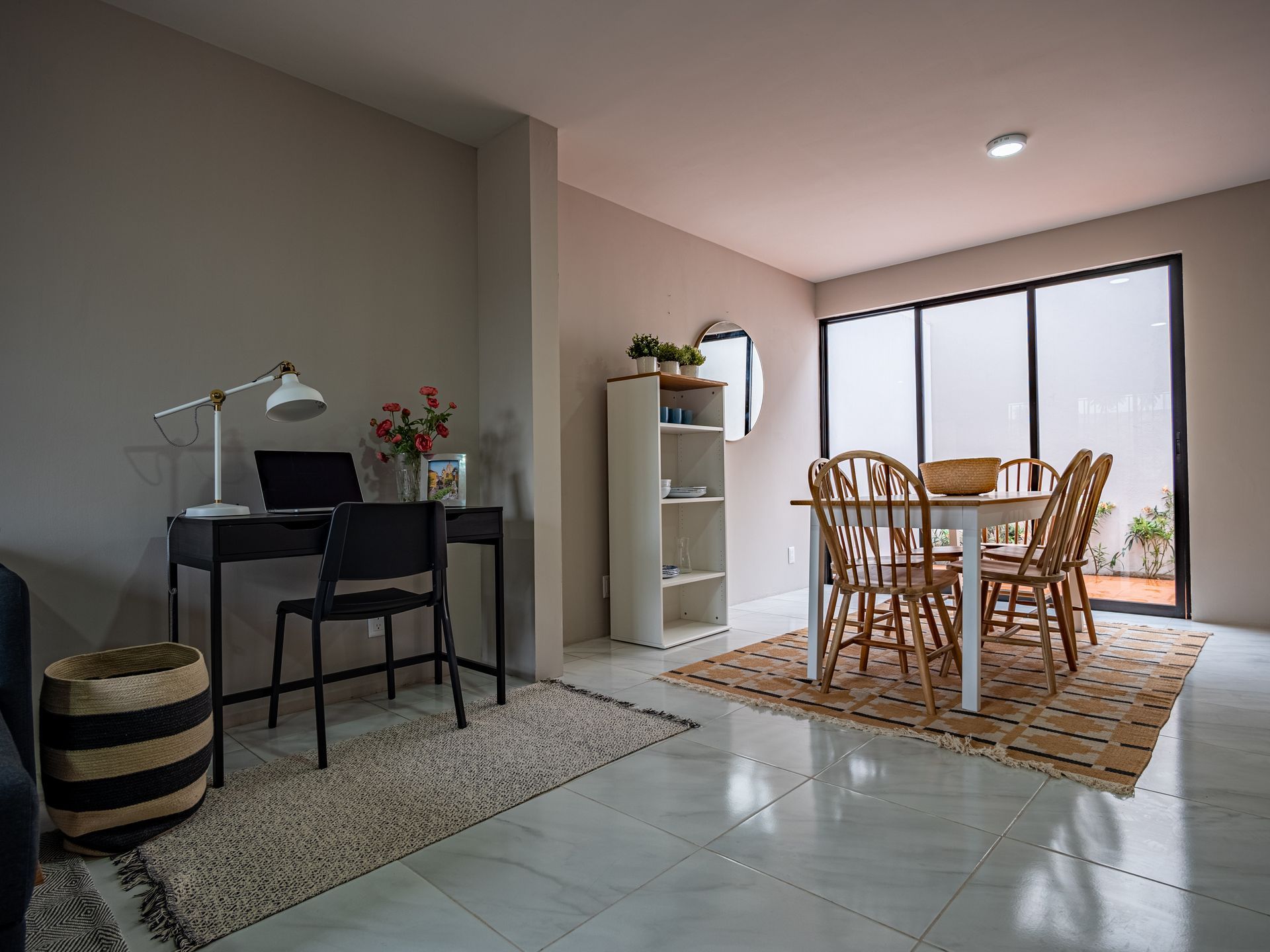 Una sala de estar con una mesa y sillas y un escritorio con una computadora portátil encima.