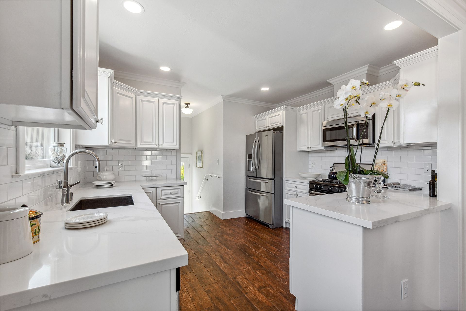 A kitchen with white cabinets , stainless steel appliances , and hardwood floors.