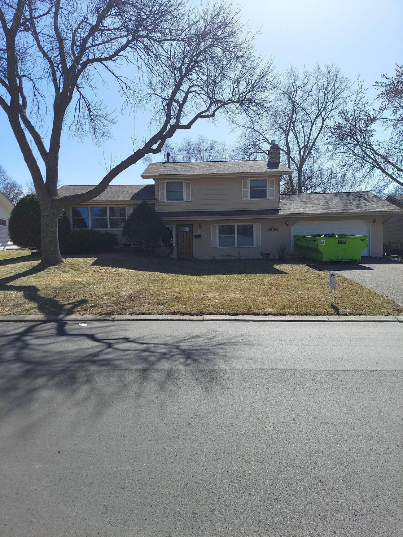 A house with a green dumpster in front of it