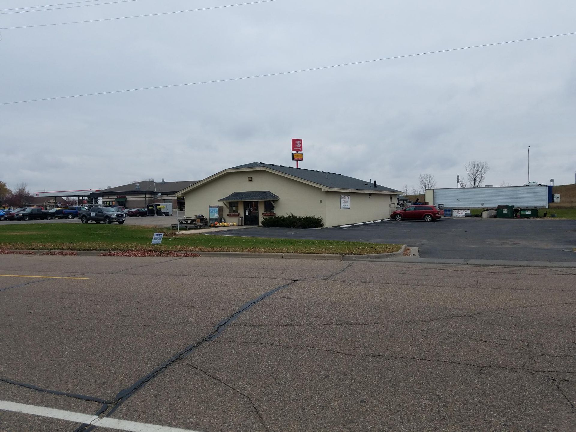 A small building is sitting on the side of a road next to a parking lot.